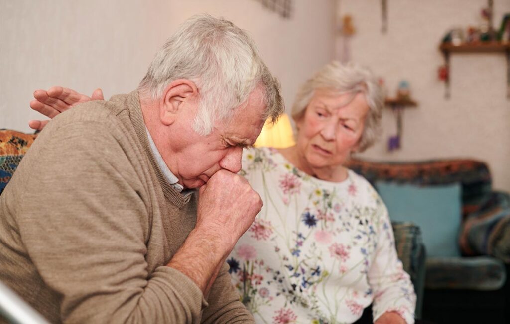 Senhor de idade acompanhado da esposa tossindo